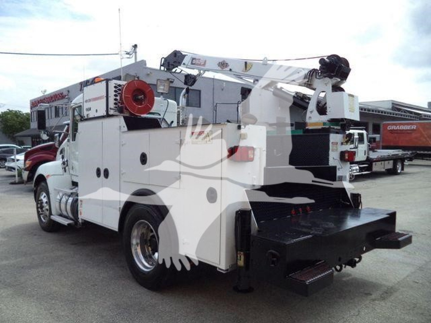 Kenworth utility service truck rear view showing crane and storage compartments, roll-up doors, and equipment mounts.