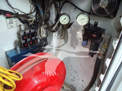 Kenworth T270 service truck interior showing gauges, wiring, and hydraulic components; red hose reel in foreground; control panel with gauges and fittings.