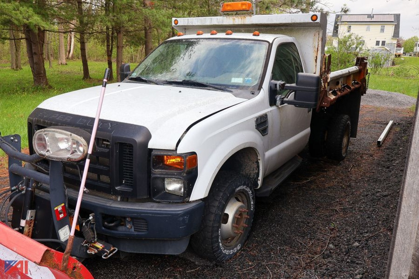Ford F-350 SD dump truck with plow, white cab, flatbed bed, front view with plow attachment and amber safety beacon on cab roof.