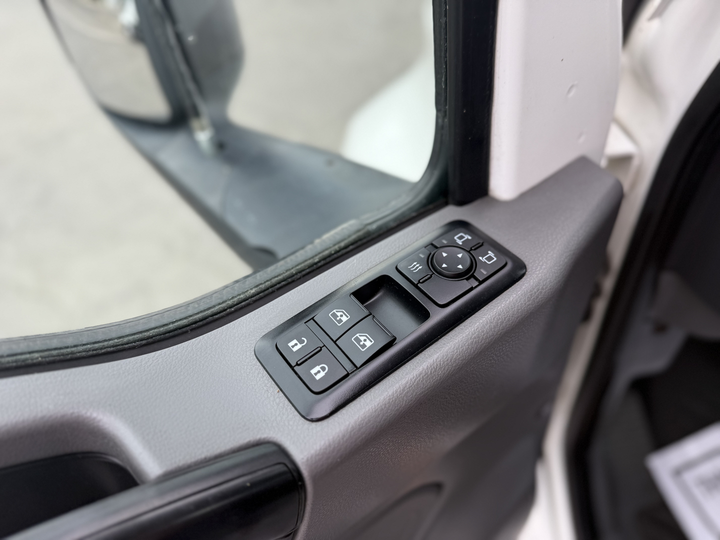 Door panel with window/lock controls of a truck cab showing mirror switch cluster and window controls.