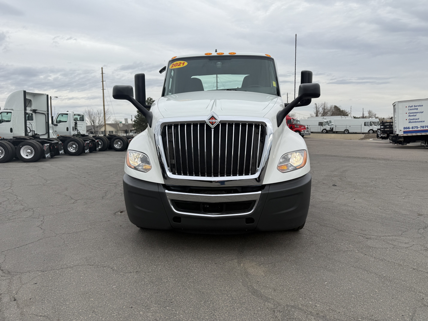 Truck front view showing International LT625 grille and headlights, white cab, black bumper, dual side mirrors.