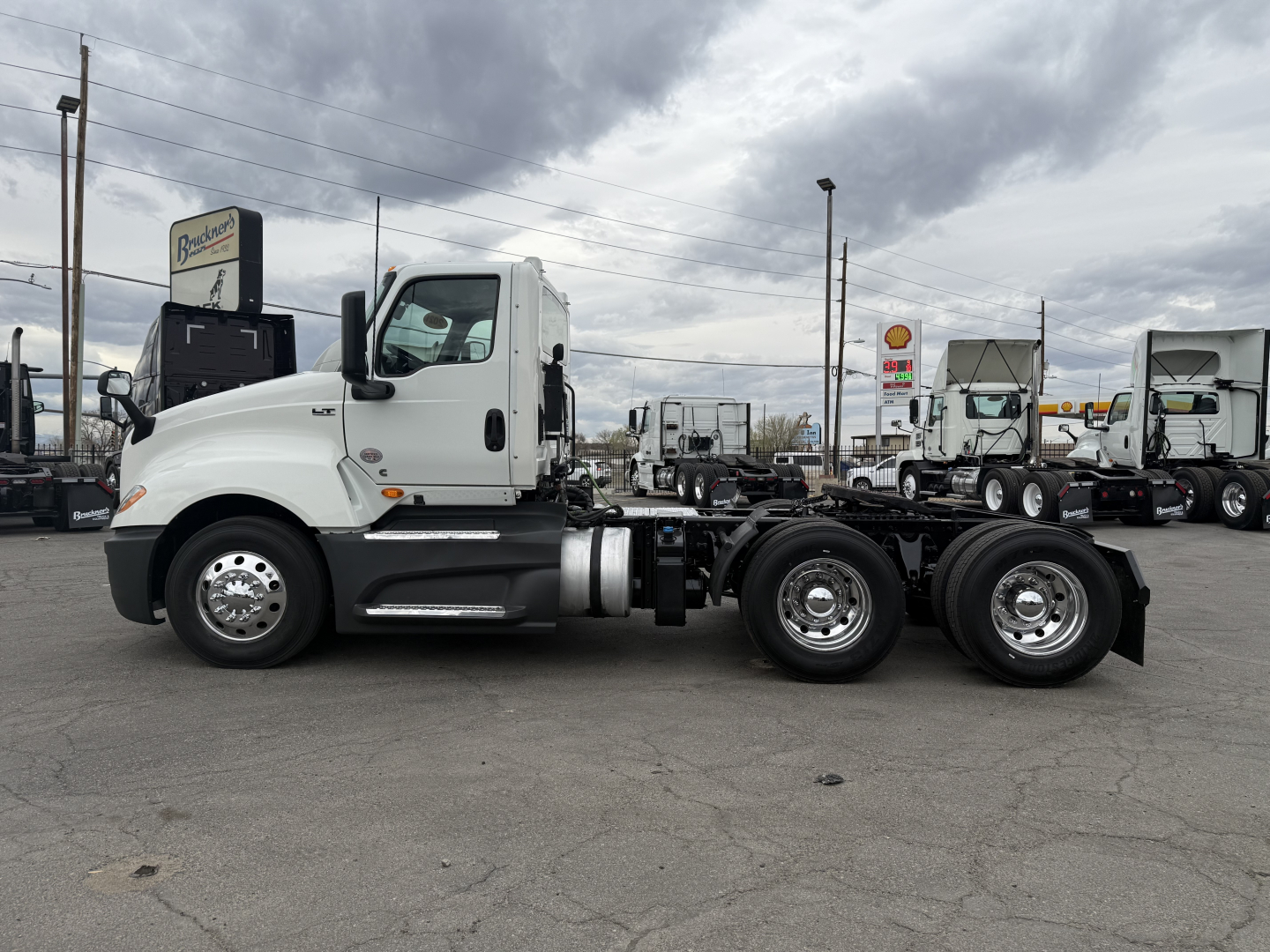 Truck chassis side view showing 2021 International LT625 cab over engine with white cab and black chassis, dual rear axles, highway trailer parking lot.