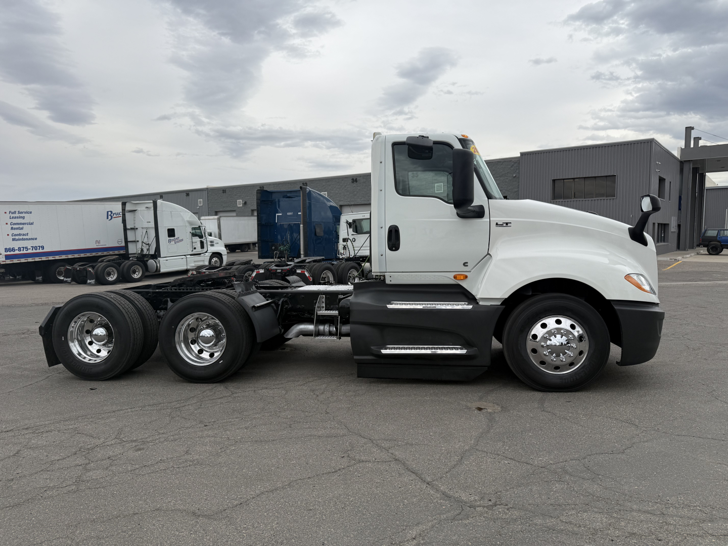 Truck side view of a white 2021 International LT625 conventional daycab, showing chassis with dual rear axles and empty bed area, with cab and wheels visible.