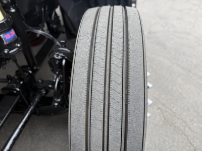 Tire tread close-up on a truck wheel with visible text on a small blue sticker nearby.