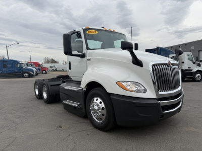 Truck cab showing 2021 International LT625 with white exterior, front grille, and dual rear axles.