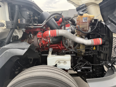 Truck engine bay showing LT625 diesel engine with red components, large intake hose, coolant reservoir, and surrounding hydraulic/air lines.