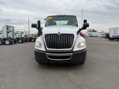 Truck front view showing International LT625 grille and headlights, white cab, black bumper, dual side mirrors.
