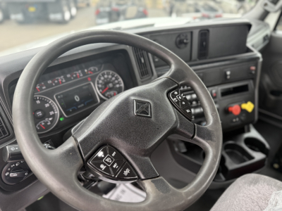 Steering wheel and dashboard view inside a 2021 International LT625 cab; visible gauges, steering wheel controls, and center console with cup holders.