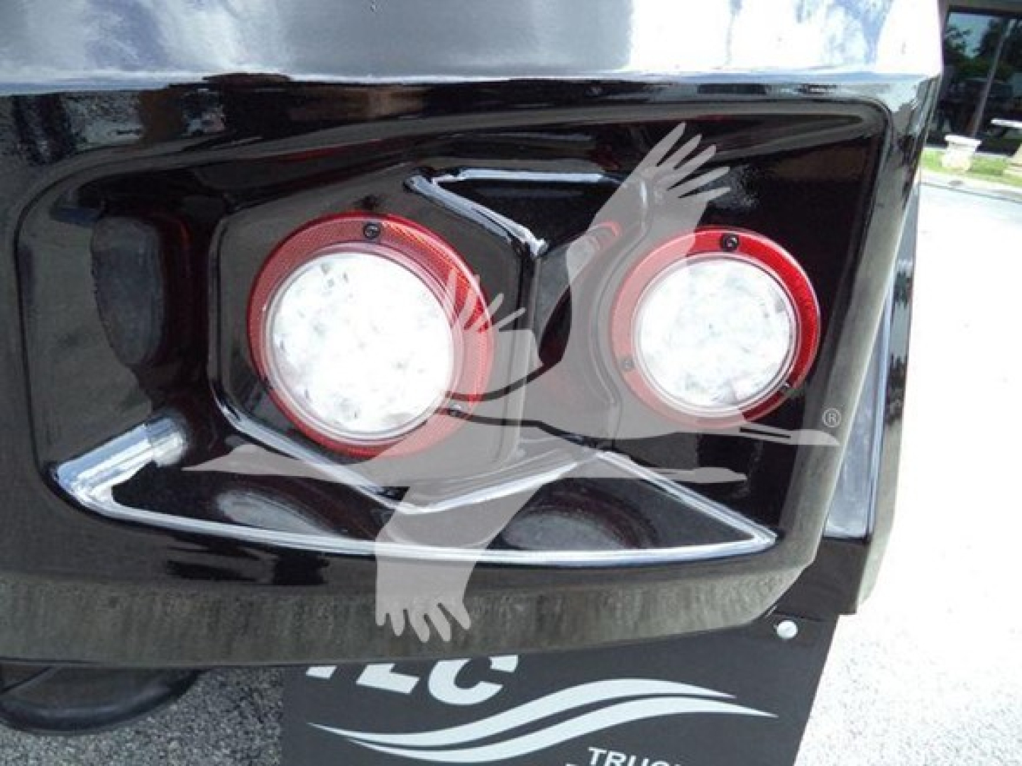 Truck front bumper with two round red-ringed headlights and a winch category badge on a glossy black surface.