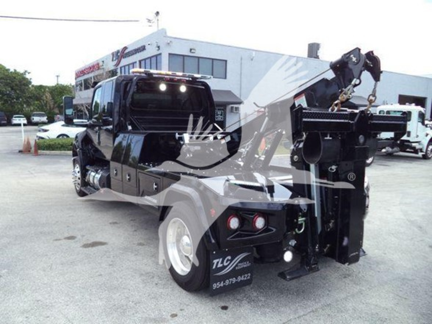 Tow truck chassis with crane arm and winch, rear view showing hydraulic boom and stabilizers, International MV front cab visible, stock number J78070.