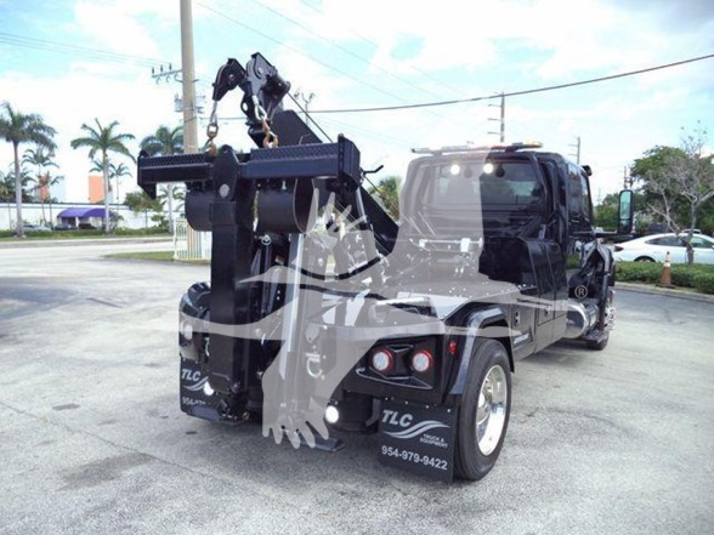 Truck with large rear hitch/winch assembly and crane hook in tow rig, bed area and dual rear tires visible.