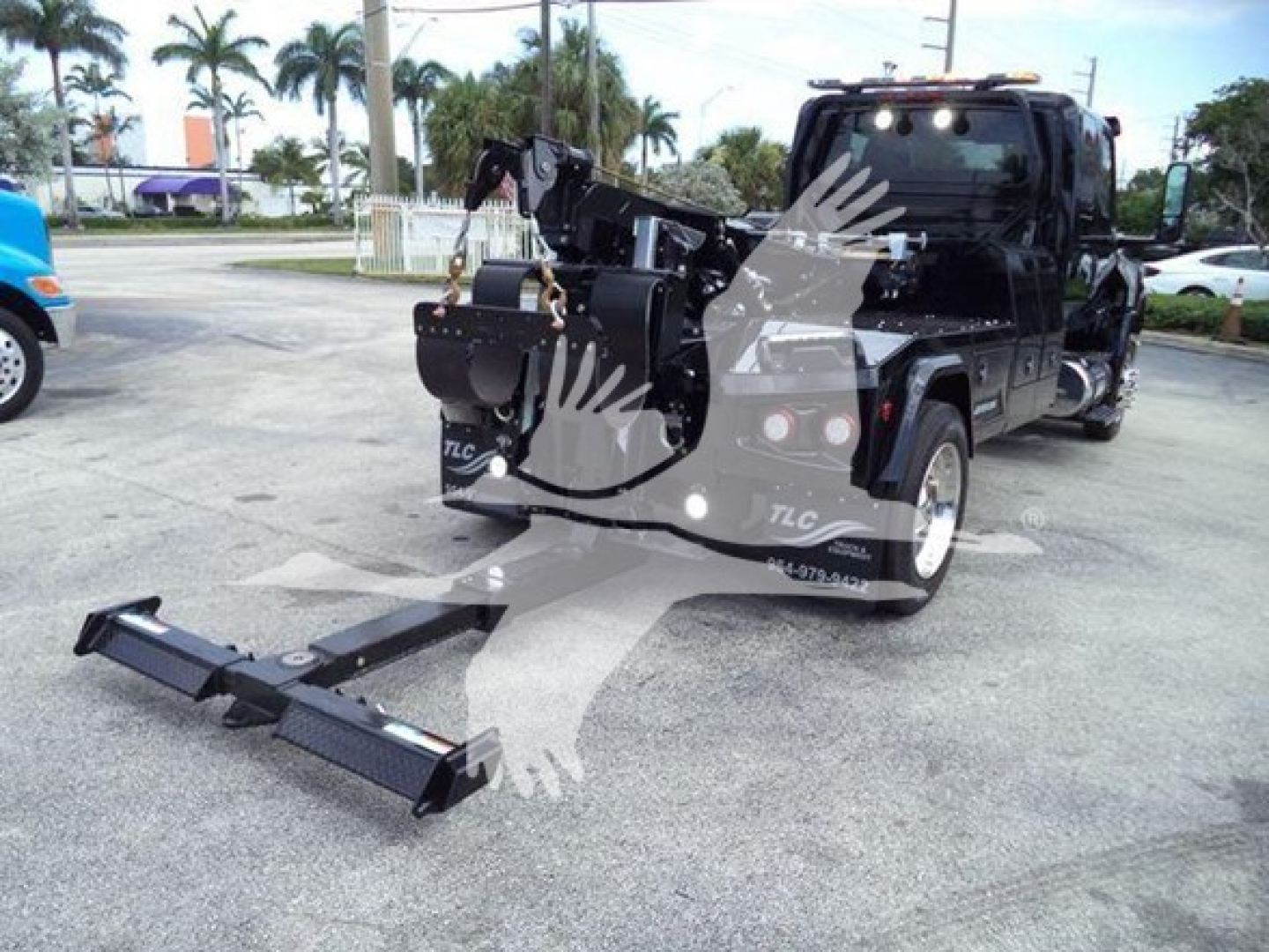 Truck cab with a front-mounted hydraulic tow or winch assembly and pull hook, International MV chassis, winch equipment attached to rear, winch bar in foreground.