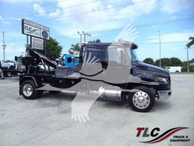 2025 International MV tow truck in service view showing cab, chassis, and winch hoist at rear with fuel tanks and chrome wheels visible.