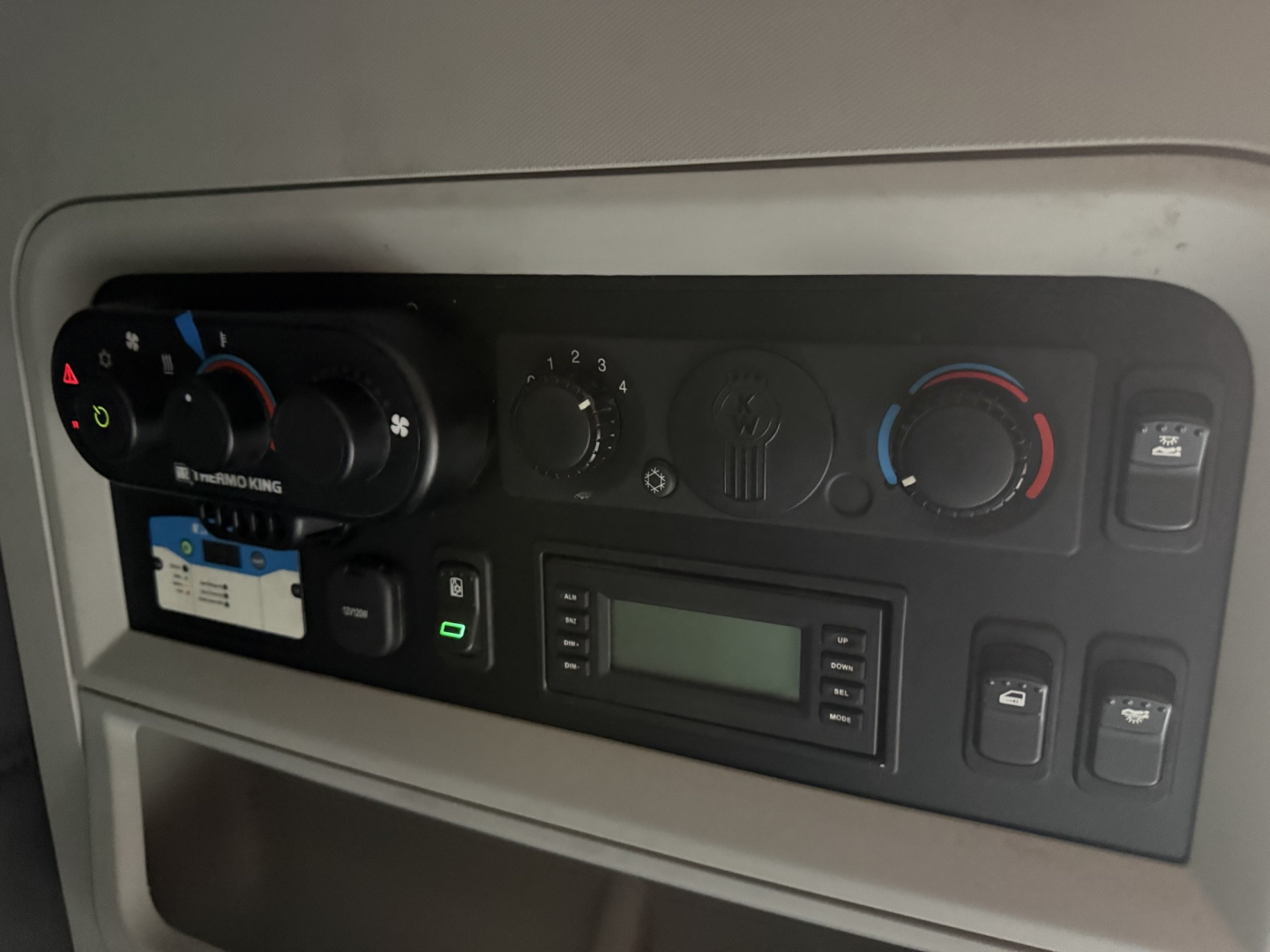 Kenworth T680 dash cluster with climate controls, radio, and switches visible in the cab interior.