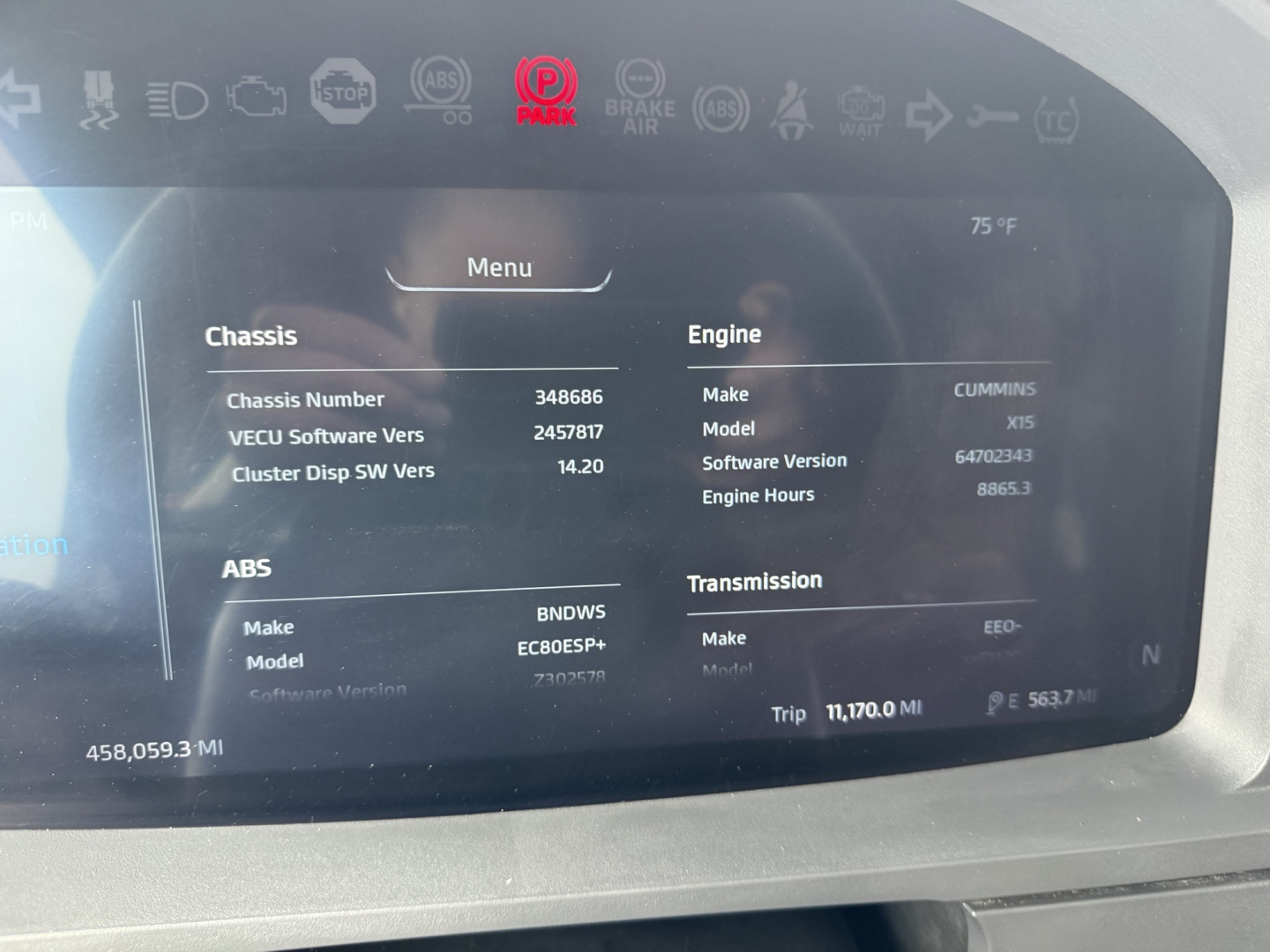 Truck instrument cluster showing Menu screen with details: Chassis number 344866, Engine Cummins X15, Transmission, ABS, VECU software version 2457, software 64702343, engine hours 8885.3, trip 11,700.0 mi, outside temperature 75°F.