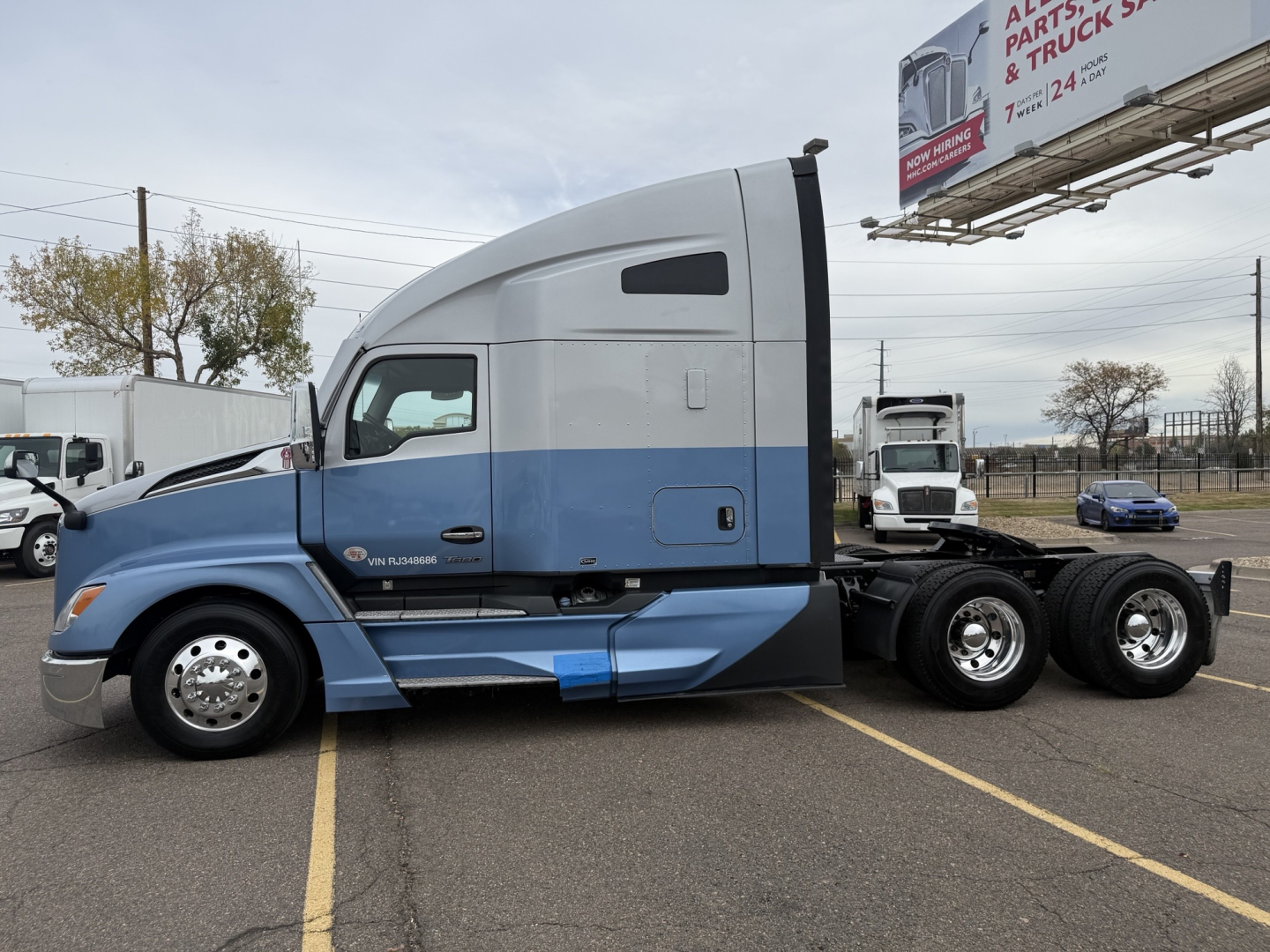 Kenworth T680 truck side view showing blue and gray cab with sleeper, chassis, and rear axles.