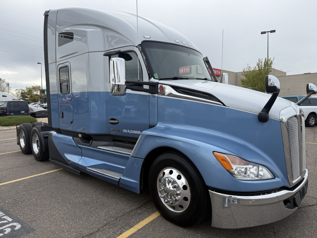 Kenworth T680 semi truck in blue and gray, side view showing cab and sleeper, chrome front bumper and wheels,VIN label not visible.