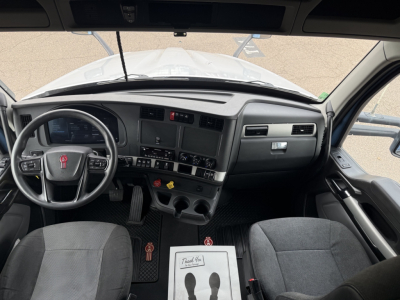 Kenworth T680 cab interior showing steering wheel dash and center controls with pedals and seats.