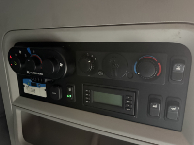 Kenworth T680 dash cluster with climate controls, radio, and switches visible in the cab interior.