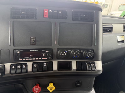 Kenworth T680 dashboard and center console showing controls, climate dials, radio, and various switches.