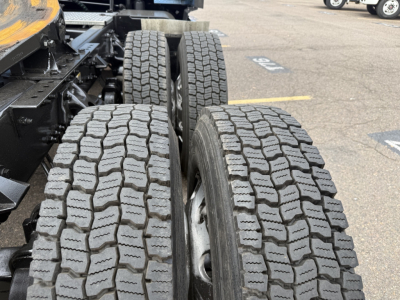Kenworth T680 truck dual rear tires and suspension viewed from side showing tread pattern and wheel wells.