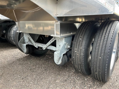 Trailer undercarriage showing dual rear axles with aluminum frame and wheel setup.