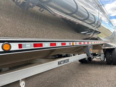 Trailer side view showing reflective tape, marker lights, and MACSIMIZER branding on the underside rail.