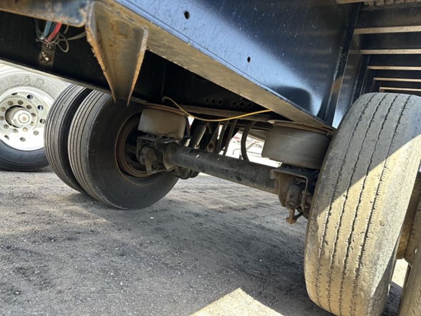 Trailer undercarriage showing rear axle and dual wheels of a used Transcraft flatbed trailer with visible suspension components.