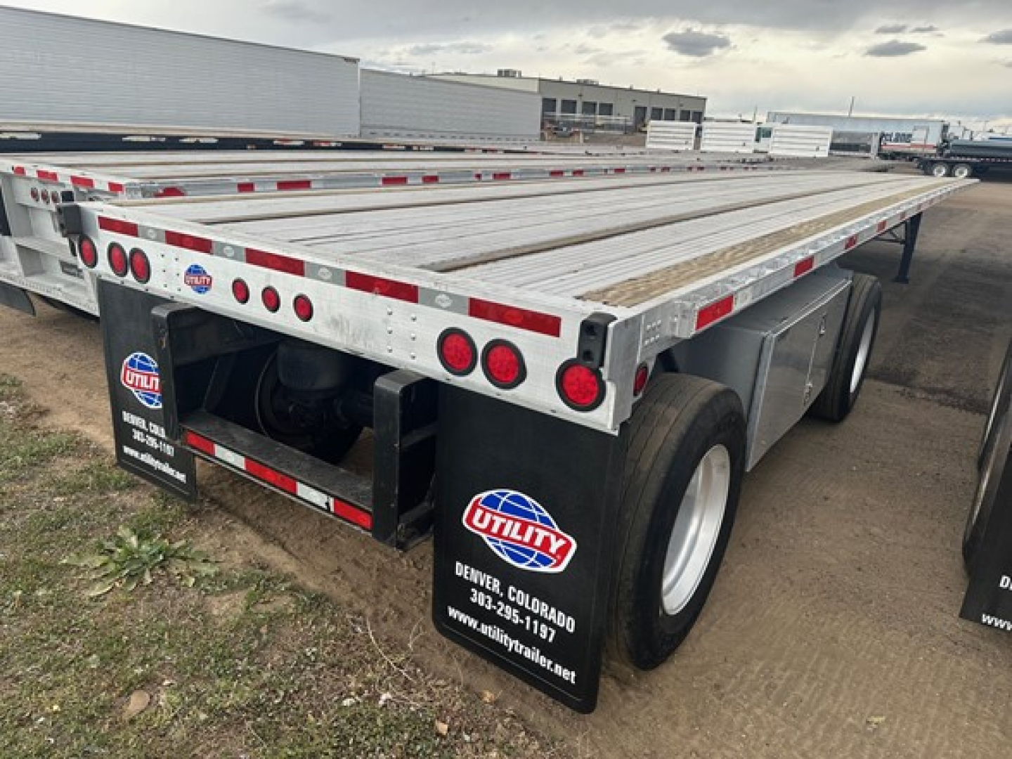 Utility trailer showing flatbed with aluminum deck and dual rear axles; Utility branding mud flaps visible.