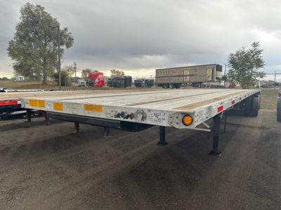 Flatbed trailer showing front and side; aluminum deck with caster/wheel area and support legs. Visible signage: yellow reflectors and taillight sections along edge.