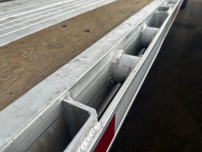 Trailer edge and deck of a 2022 Utility 4000 Ae flatbed trailer showing aluminum frame, wood deck, and stake pocket. 