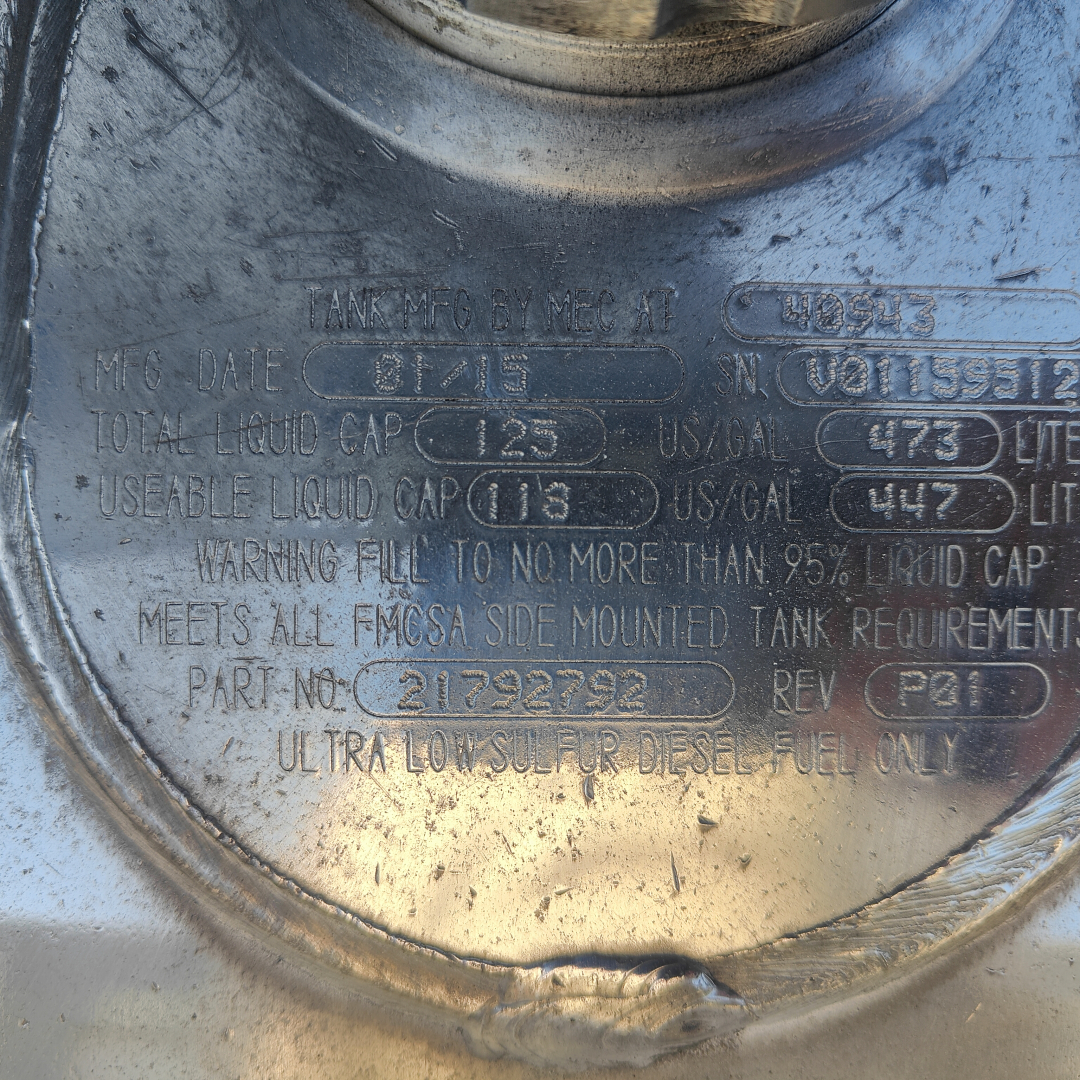 Tank/diesel fuel tank imprint showing manufacturer and capacity information. Visible text includes multiple fields: MFG DATE 08/15? Total liquid capacity 125? Useable liquid cap 118? US gal 473? Part numbers and warnings. Ultra low sulfur d
