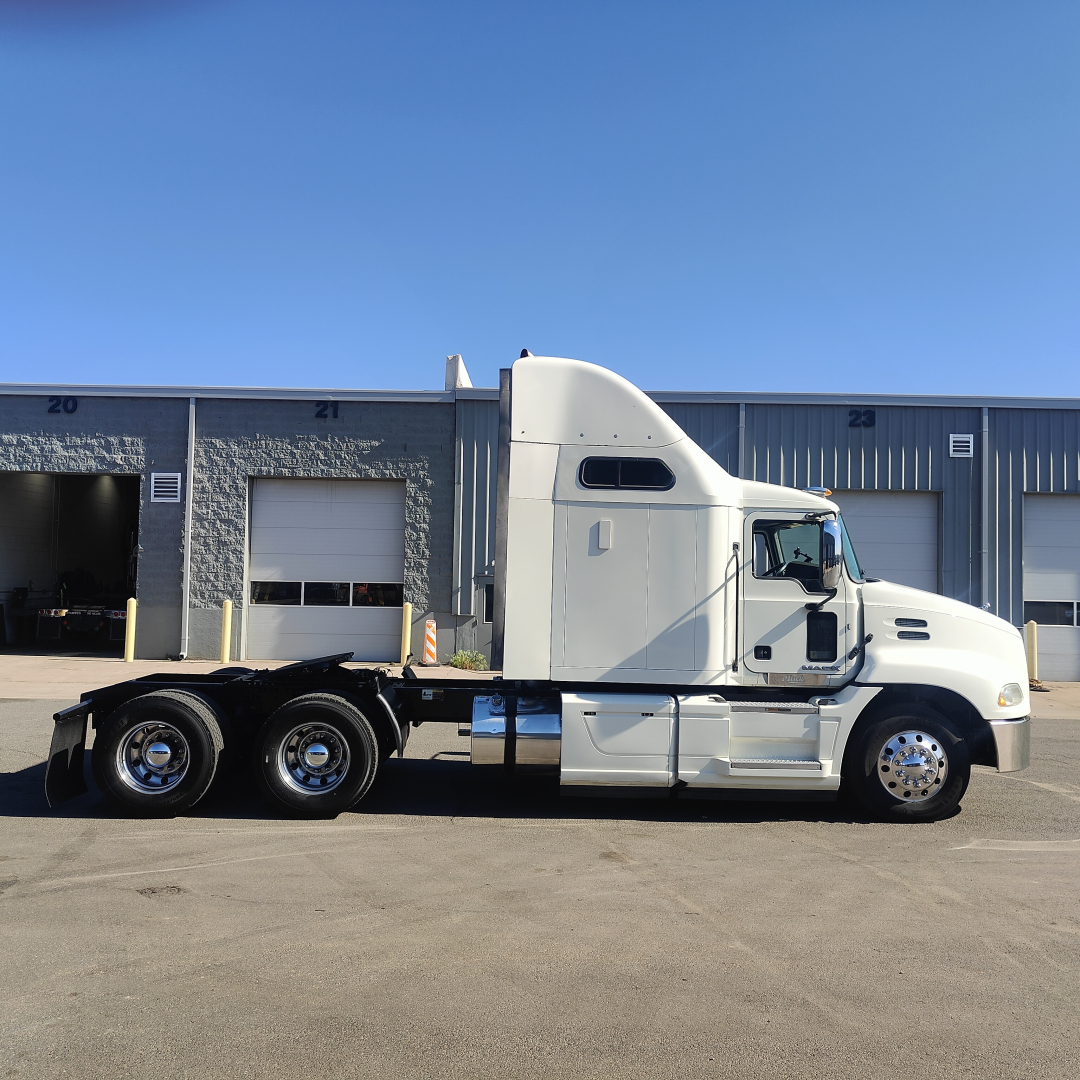 Semi truck tractor side view showing sleeper cab and two rear axles in silver exterior.