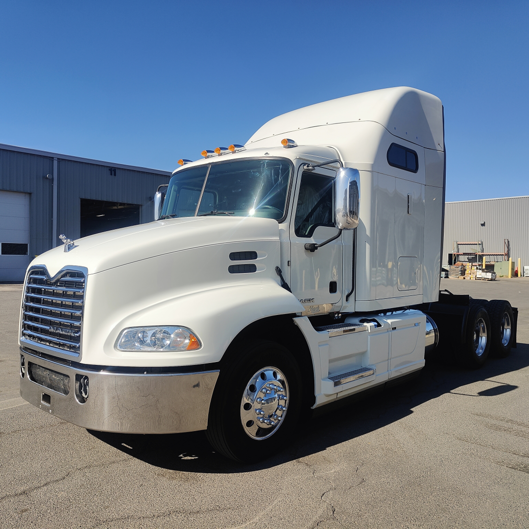 Truck cab in-service 2016 Mack CXU613 front-left view showing sleeper cab, chrome grille, dual rear axles, white paint, and mirrors.