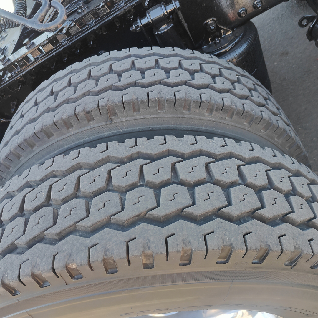 Truck axle and dual rear tires showing heavy tread, part of a Mack CXU613 truck.