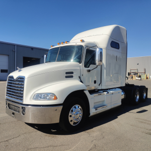 Truck cab in-service 2016 Mack CXU613 front-left view showing sleeper cab, chrome grille, dual rear axles, white paint, and mirrors.