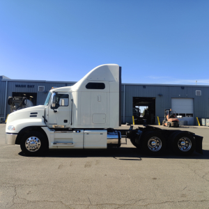 Truck side view showing a white 2016 Mack CXU613 sleeper cab tractor with dual rear axles and chrome wheels.
