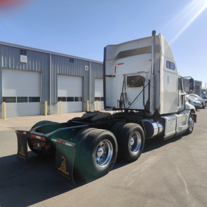 Truck tractor cab and rear wheels visible in a parking lot with a sleeper, rear fenders and mudflaps.