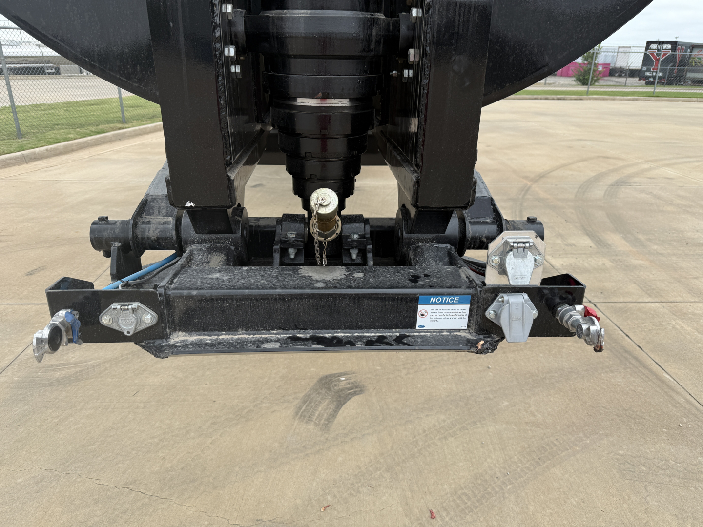 Dump trailer hitch and front frame showing coupling and markings on bumper