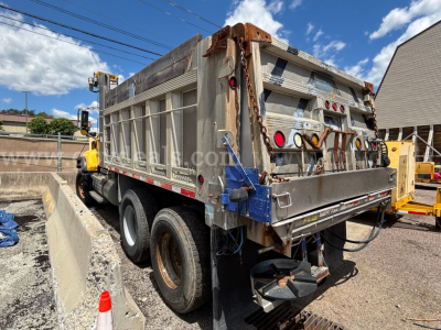 Dump truck rear and left side of a 2006 Mack CV713 with a gray open-top dump bed, dual rear axles, and taillights; stock number 30360-461 visible on body.