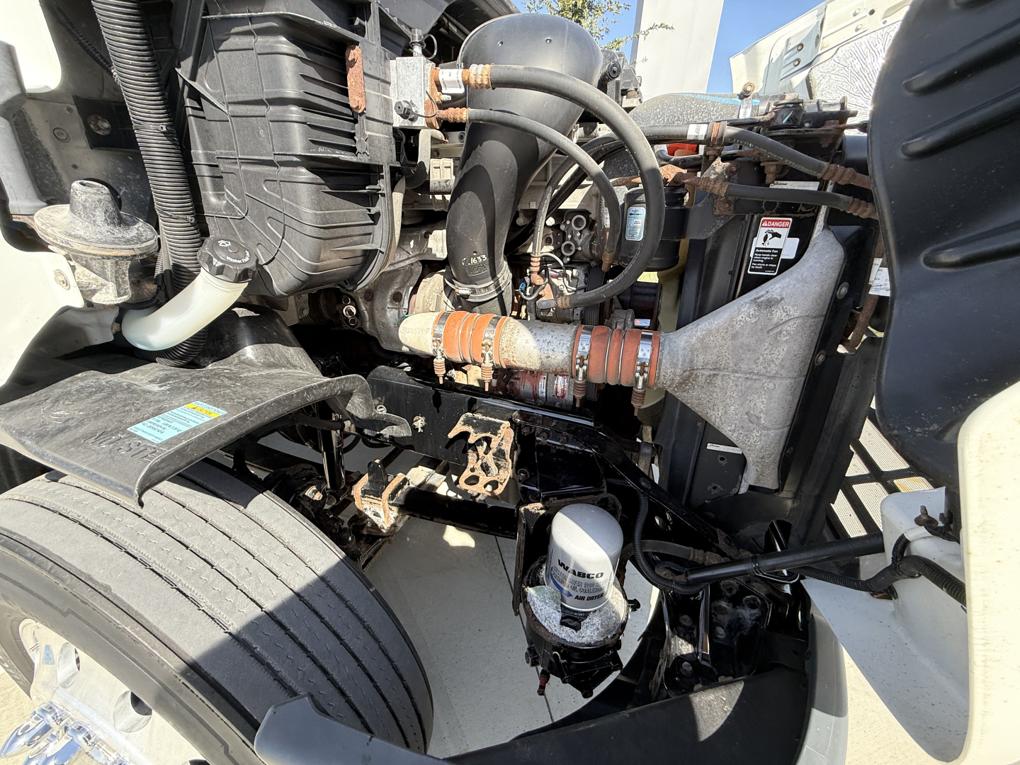 Truck engine bay showing air intake, hoses, and filtration system in a Freightliner CA11364DC daycab.