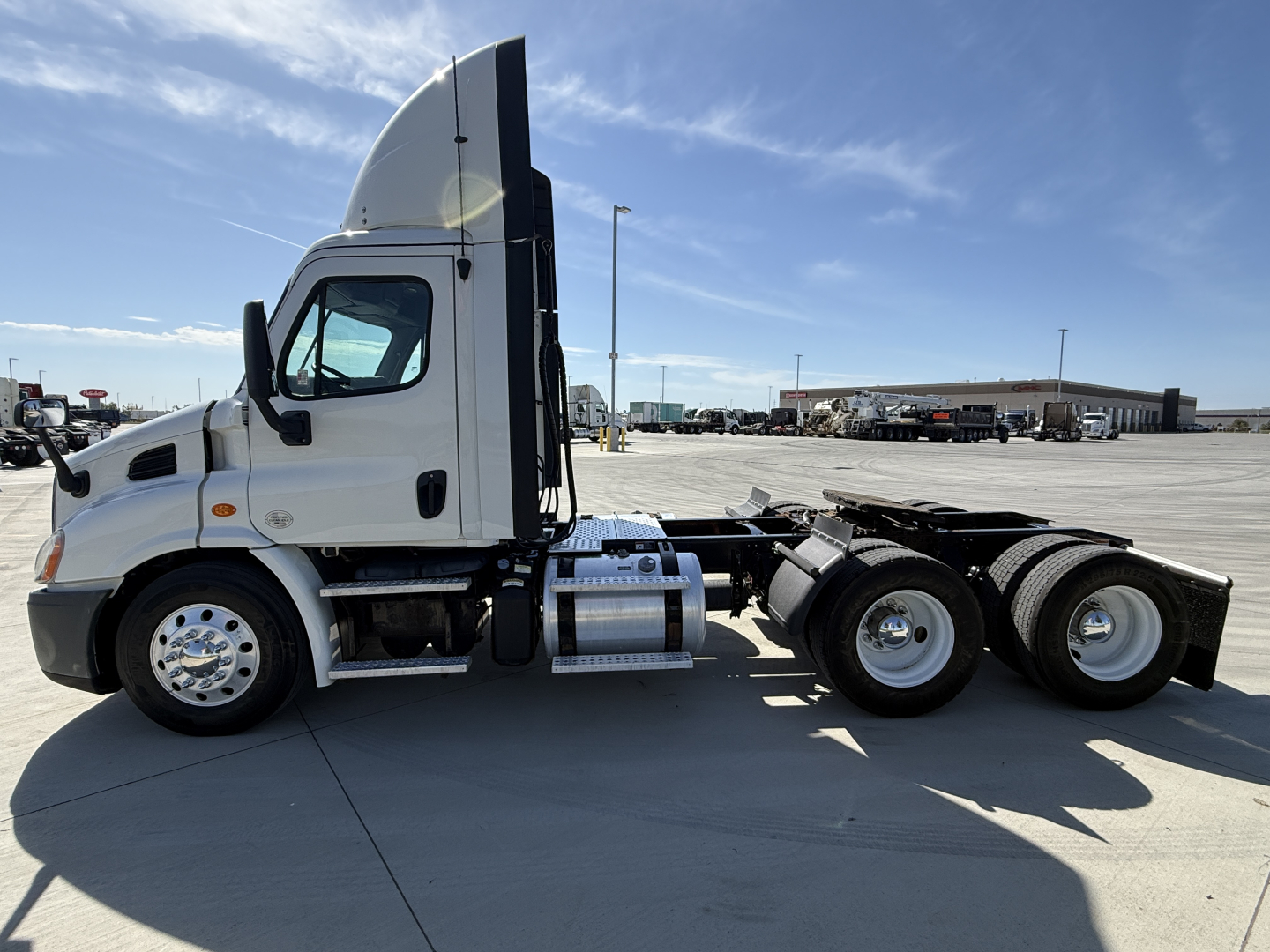 2019 Freightliner CA11364DC semi truck tractor cab side view with fuel tanks and dual rear axles.