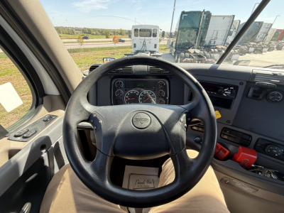 Truck cab interior showing steering wheel and gauge cluster, dashboard controls visible.