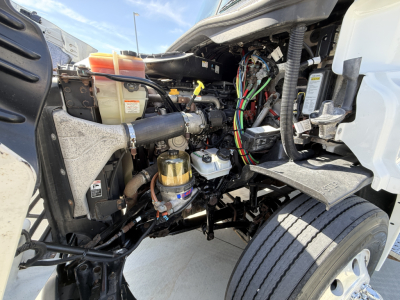 Truck engine bay of a 2019 Freightliner CA11364DC exterior view showing engine components, wiring harness, coolant reservoir, and air filter housing.