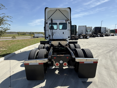 Conventional daycab tractor rear view showing chassis and rear tires with mud flaps and tail lights.