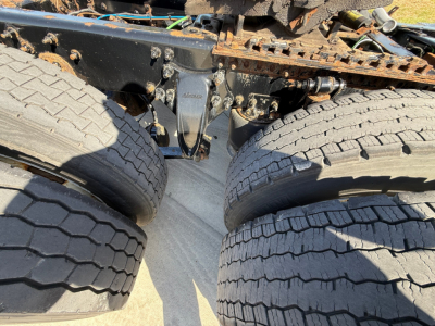 Truck rear view showing dual rear axles and suspension components under a Freightliner daycab chassis.