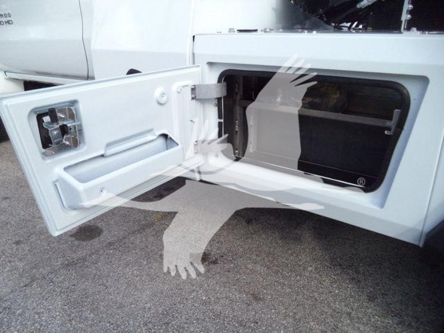 Truck side storage cabinet door open showing recessed compartment with a latch and a small knob.