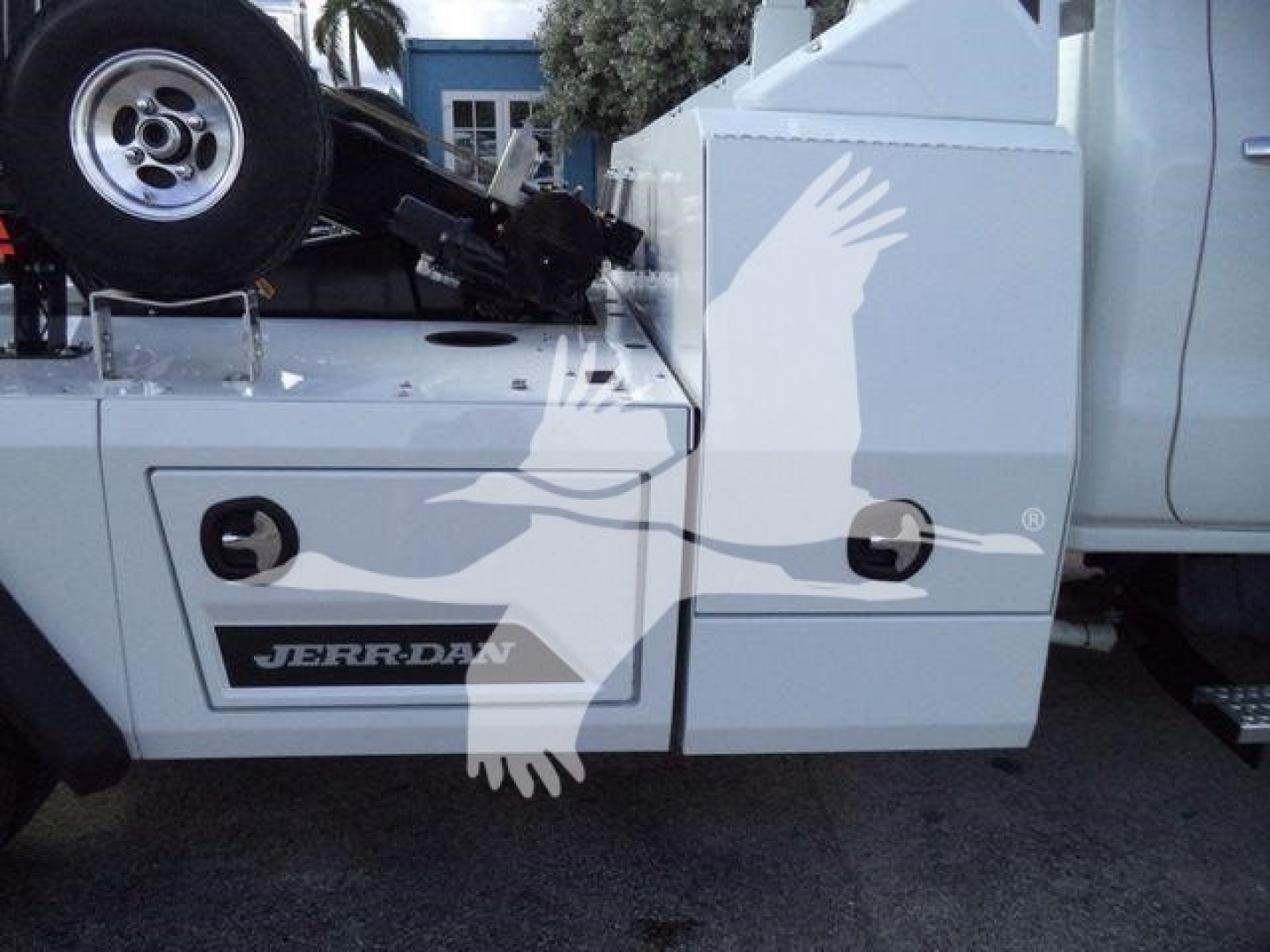 Truck bed area of a Chevrolet Silverado 6500HD with a mounted winch and a Jerr-Dan storage box; visible components include a spare tire, toolbox doors, and hydraulic winch housing.