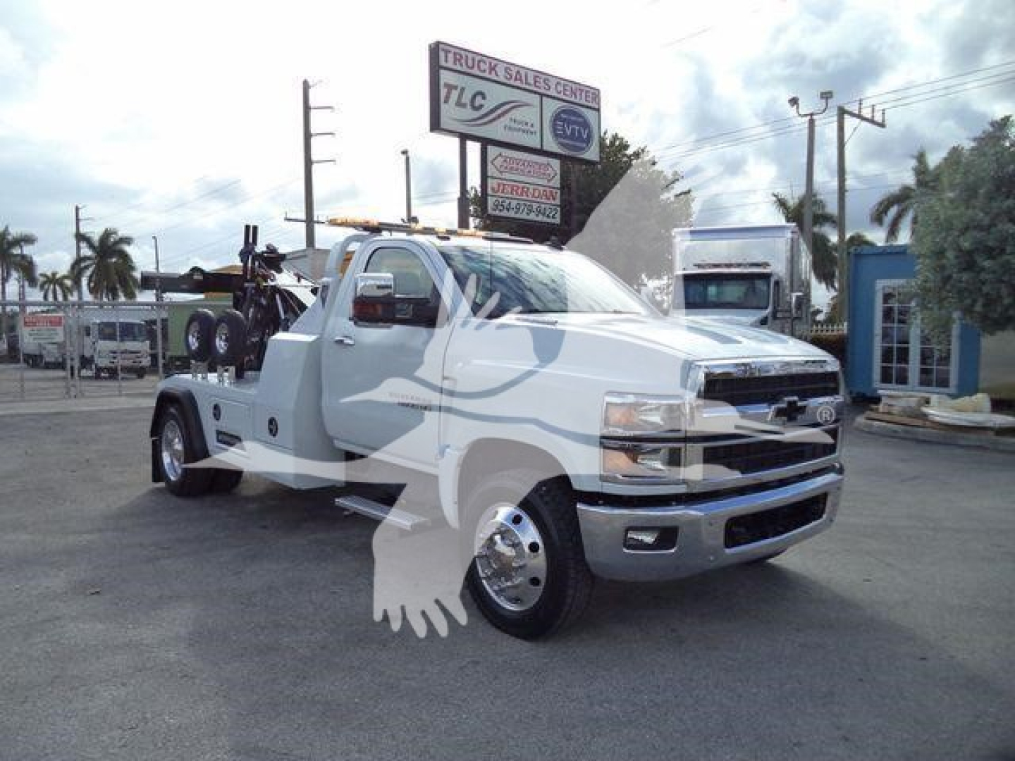 Truck showing a white 2023 Chevrolet Silverado 6500HD in a lot with a winch setup and crane on the bed.