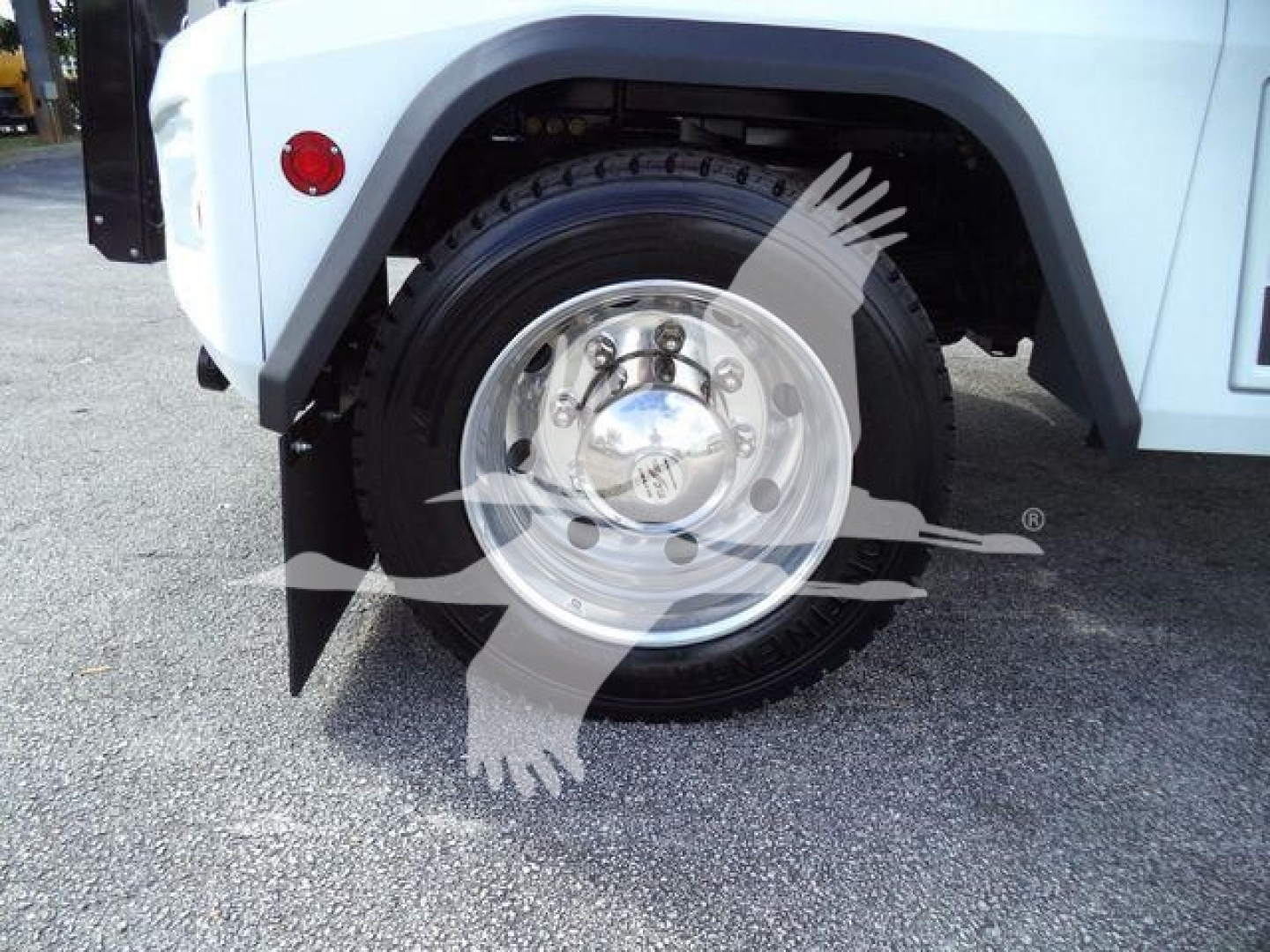 Truck wheel well and front tire of a light blue 2023 Chevrolet Silverado 6500HD chassis with a polished hubcap and black fender. Visible text on wheel center cap and surrounding components.
